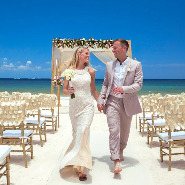 A wedding couple walking down the aisle on the beach