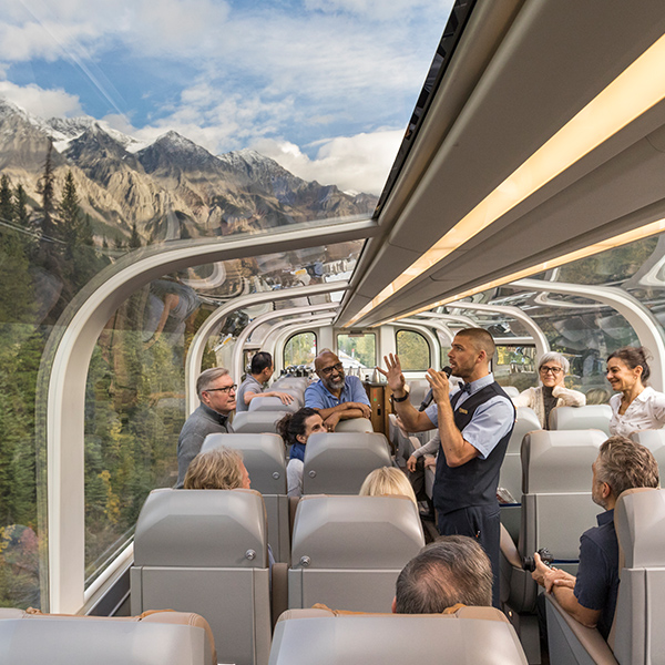 People riding through the mountains in a glass dome train